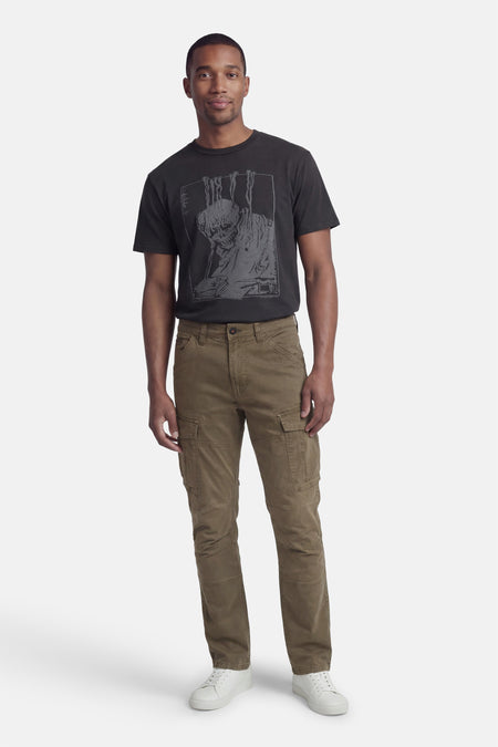 Pantalon cargo vert par Petrol Industries®, avec poches cargo et porté avec un t-shirt noir et des chaussures blanches.