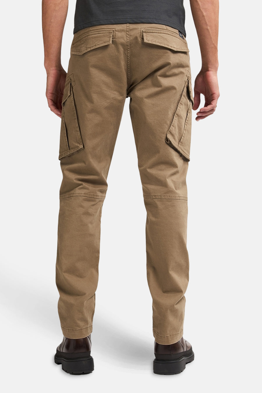 Pantalon cargo écru par Petrol Industries, avec poches latérales et arrière, porté avec des chaussures foncées.
