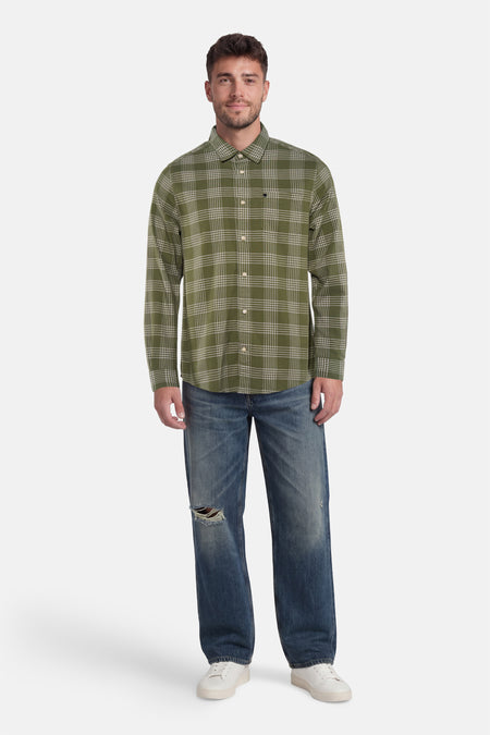 Chemise verte à carreaux de BARBOUR à manches longues, portée avec un jean déchiré et des baskets blanches.