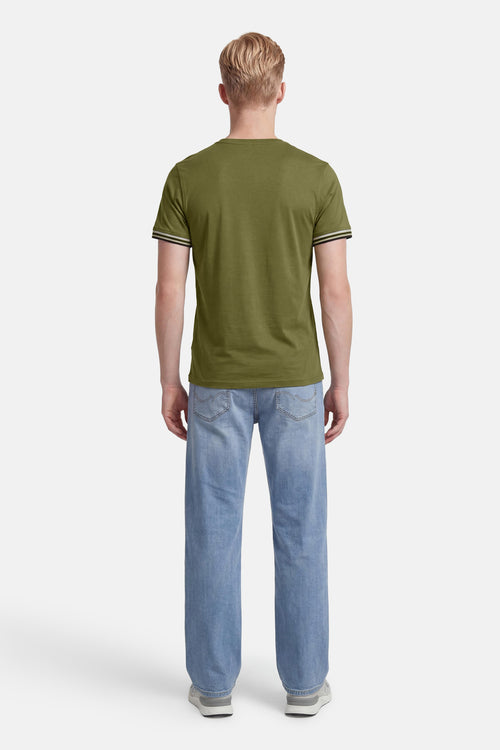T-shirt vert de BARBOUR à manches courtes avec poignets côtelés rayés, vu de dos, porté avec un jean bleu et des baskets grises.