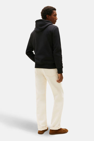 Sweat noir à capuche de TOMMY JEANS, porté avec un jean clair et des mocassins marron.