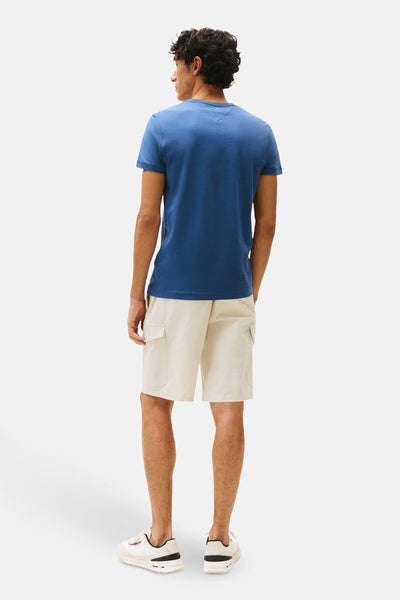 T-shirt bleu à manches courtes de Tommy Hilfiger, porté avec un short beige cargo et des baskets blanches, vue de dos.