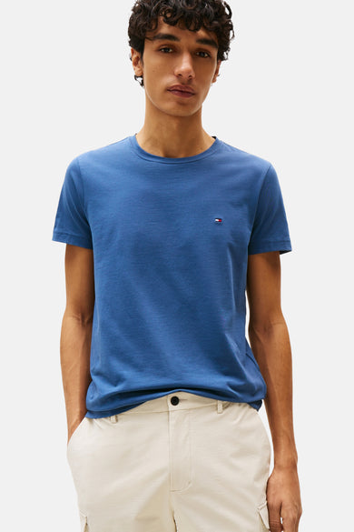 T-shirt bleu à manches courtes de TOMMY HILFIGER, porté avec un pantalon couleur crème.