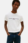 White short-sleeve T-shirt by TOMMY JEANS with navy and red logo print, worn with dark blue jeans, front view.