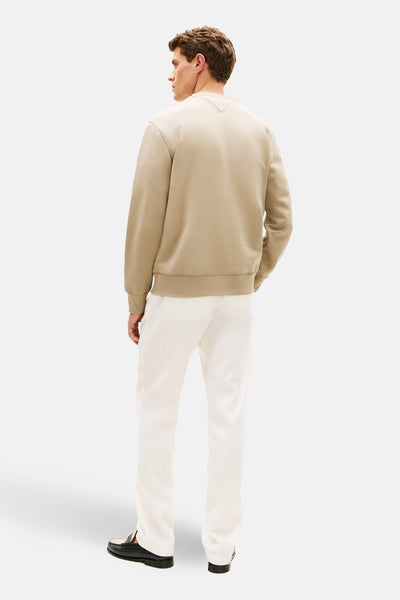 Kaki sweatshirt van TOMMY HILFIGER, van achteren gezien, gedragen met een witte broek en zwarte loafers.