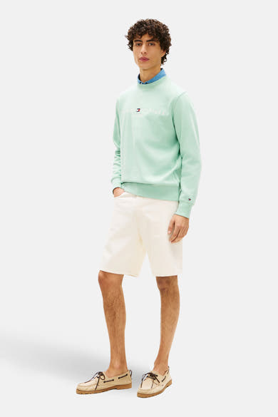 Sweat-shirt vert de TOMMY HILFIGER, porté avec une chemise en jean, un short beige et des chaussures bateau marron clair.
