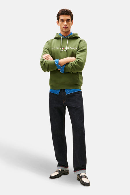 Sweat vert à capuche de TOMMY HILFIGER, porté sur une chemise en denim, avec un jean foncé et des mocassins.