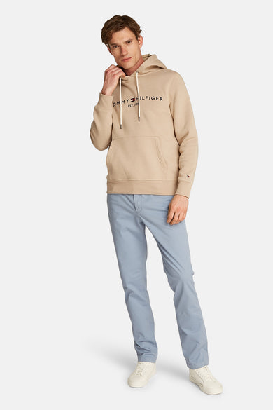 Sweat beige à capuche de Tommy Hilfiger, porté avec un pantalon bleu clair et des baskets blanches.