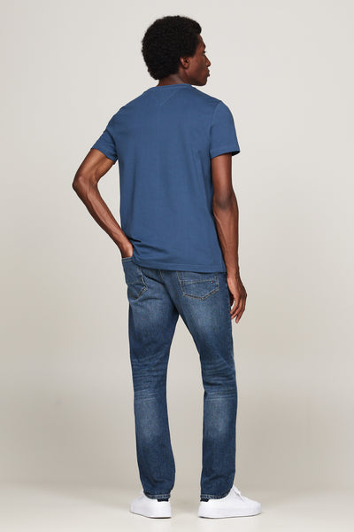 T-shirt bleu à manches courtes de TOMMY HILFIGER, porté avec un jean et des baskets blanches, vue de dos.
