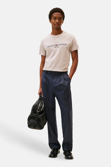 Beige T-shirt met korte mouwen van TOMMY HILFIGER, gedragen met een blauwe broek en een zwarte tas.