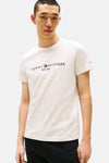 Beige T-shirt met korte mouwen van Tommy Hilfiger, gedragen met een zwarte jeans en loafers.