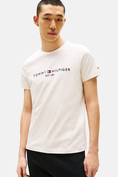 Beige T-shirt met korte mouwen van Tommy Hilfiger, gedragen met een zwarte jeans en loafers.