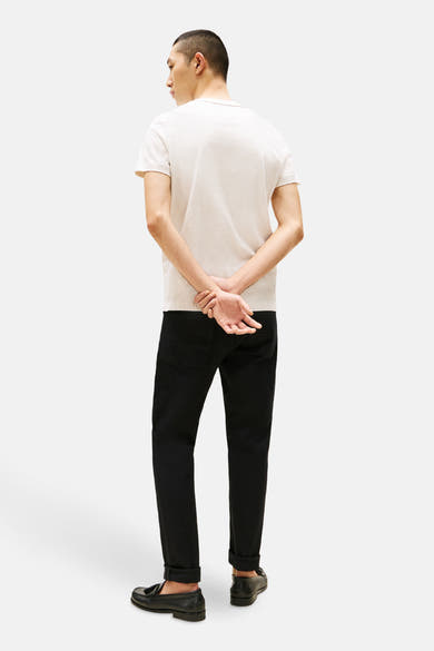 T-shirt à manches courtes beige de Tommy Hilfiger, porté avec un jean noir et des mocassins.