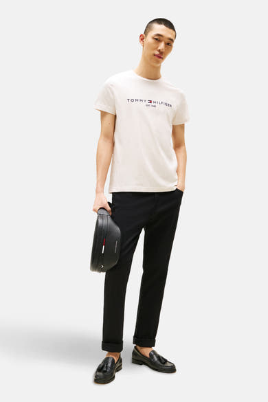 Beige T-shirt met korte mouwen van TOMMY HILFIGER, gedragen met een opgerolde zwarte broek en zwarte kwast loafers.