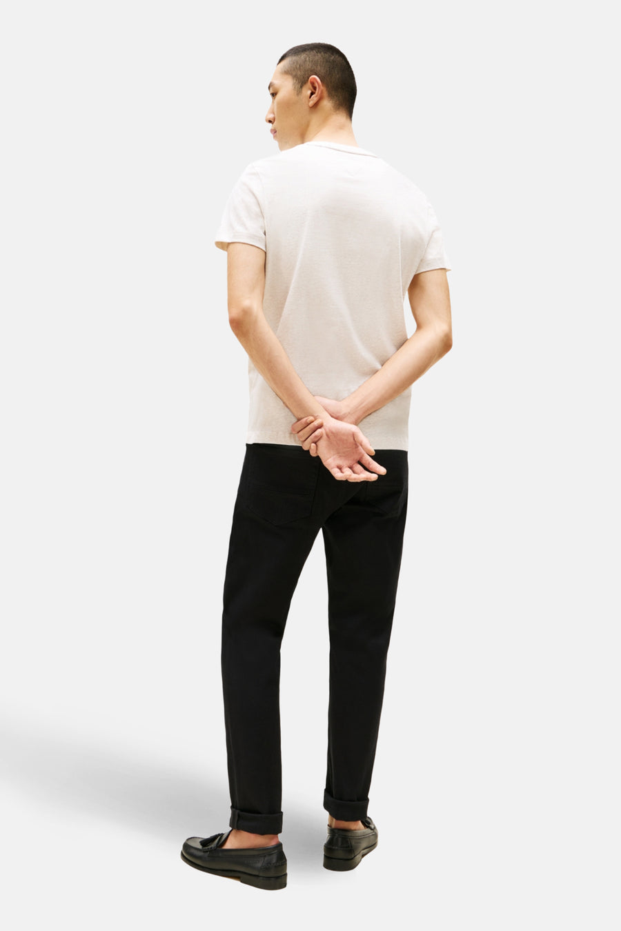 Beige T-shirt met korte mouwen van TOMMY HILFIGER, gedragen met een zwarte broek en leren loafers, achterzijde.