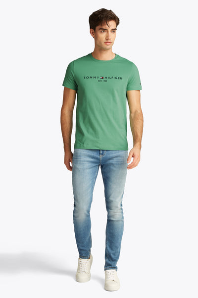 T-shirt à manches courtes vert de TOMMY HILFIGER, porté avec un jean délavé et des baskets blanches.