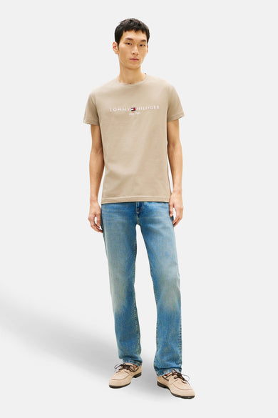 T-shirt à manches courtes beige de TOMMY HILFIGER, porté avec un jean bleu et des chaussures bateau.