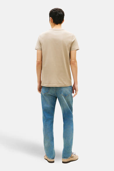 Beige T-shirt met korte mouwen van TOMMY HILFIGER, gedragen met een blauwe spijkerbroek en bootschoenen, achtergezicht.