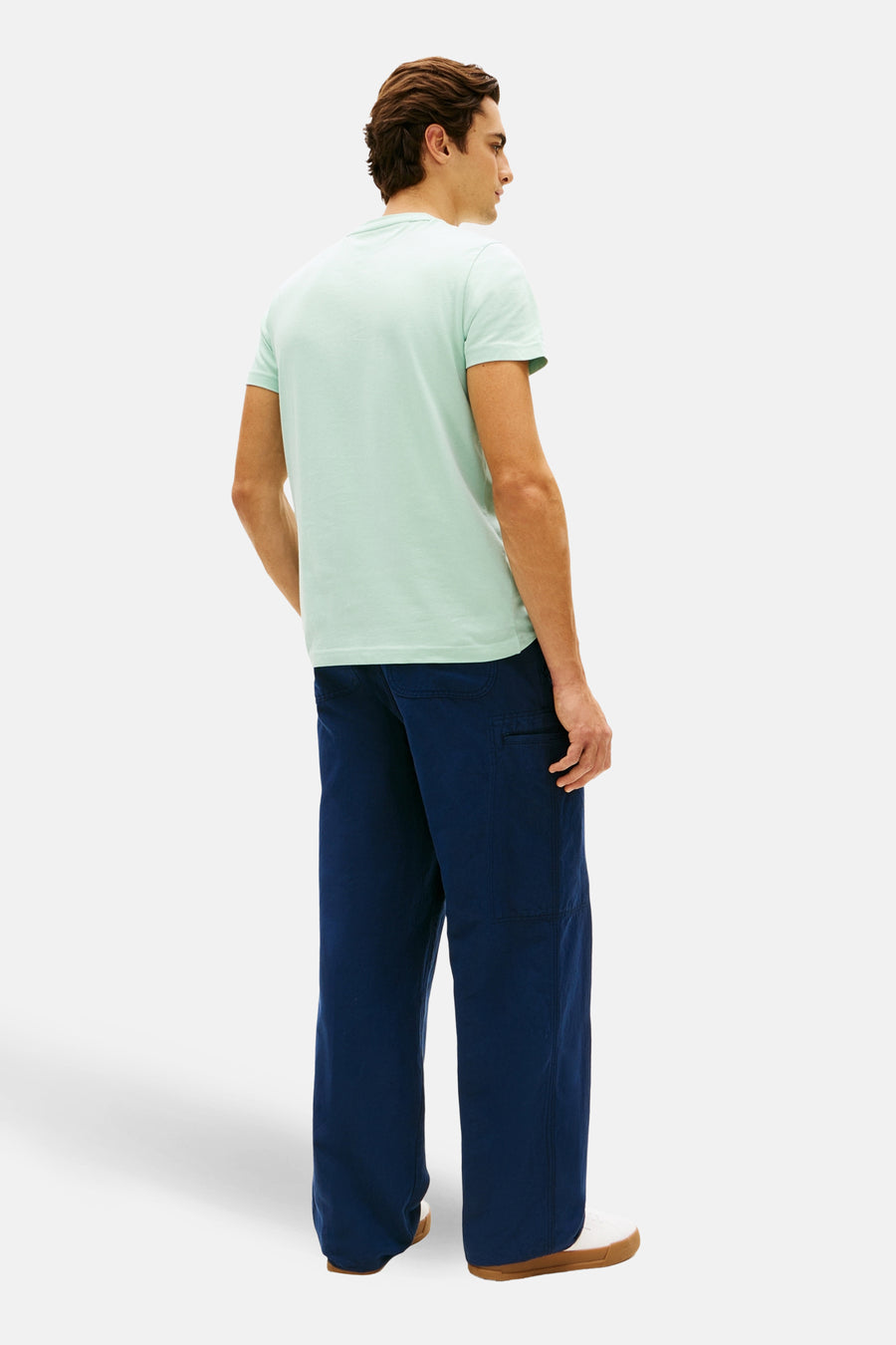 T-shirt à manches courtes vert, par TOMMY HILFIGER, porté avec un pantalon bleu marine décontracté.