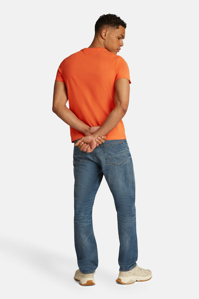 Oranje T-shirt met korte mouwen van TOMMY HILFIGER, gedragen met een blauwe spijkerbroek en beige schoenen, achterzijde.