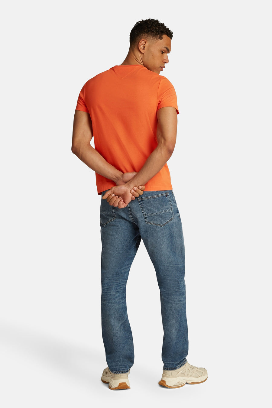T-shirt orange à manches courtes de TOMMY HILFIGER, porté avec un jean bleu et des chaussures beiges, vue de dos.