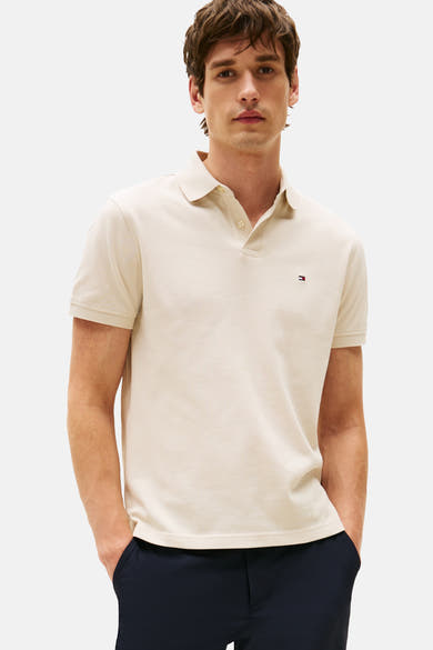 Polo beige met TOMMY HILFIGER, gedragen in een blauwe korte broek en witte sneakers.