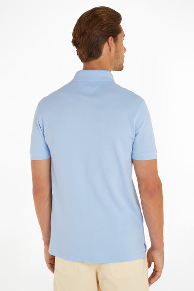 Light blue polo shirt back view, ribbed collar and cuffs, piqué texture, worn with beige trousers