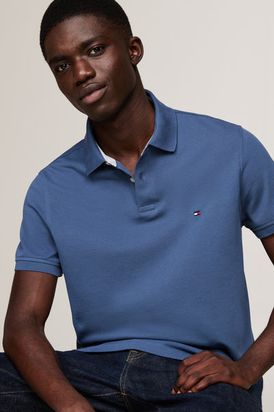 Polo bleu à manches courtes de TOMMY HILFIGER, porté avec un jean, sur un modèle masculin.
