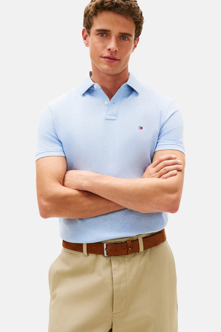 Blauwe polo met korte mouwen van TOMMY HILFIGER, gedragen met een beige chino en bruine bootschoenen.