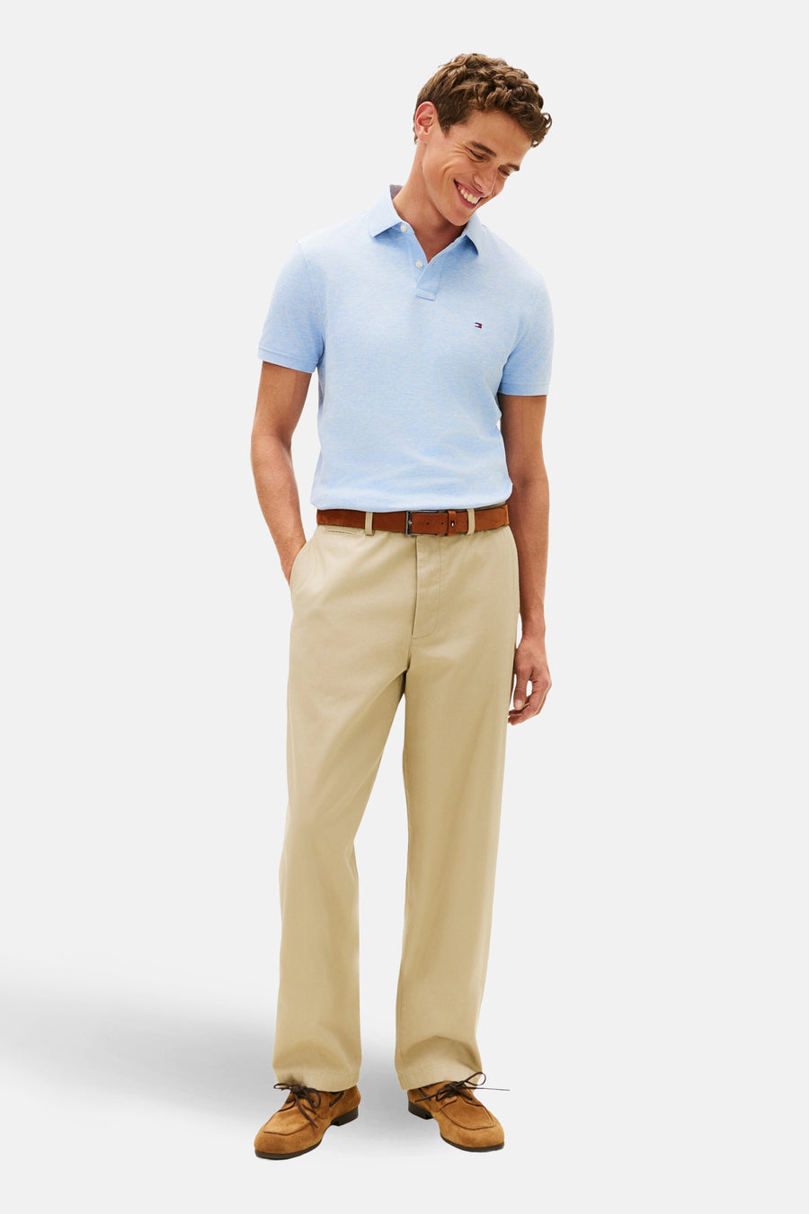 Polo bleu à manches courtes de TOMMY HILFIGER, porté avec un pantalon chino beige et des chaussures bateau marron.
