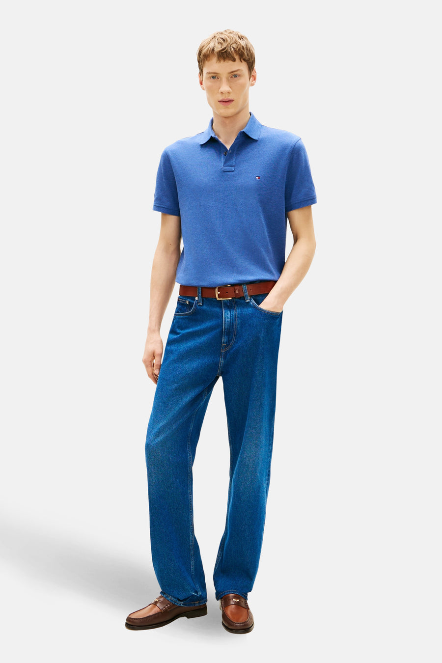 Polo à manches courtes bleu de TOMMY HILFIGER porté avec un jean et des mocassins marron.