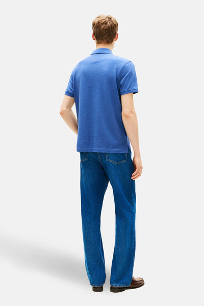 Polo à manches courtes bleu de TOMMY HILFIGER, porté avec un jean et des chaussures marron, vue de dos.
