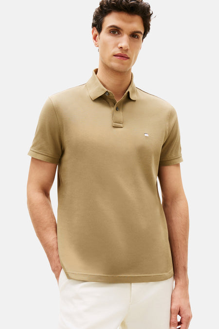 Korte mouwen poloshirt van TOMMY HILFIGER, gedragen met een witte broek en witte sneakers.
