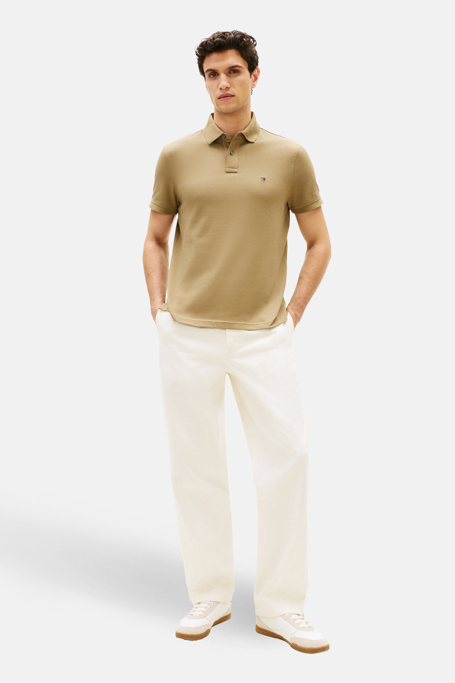 Polo kaki à manches courtes de TOMMY HILFIGER, porté avec un pantalon blanc et des baskets blanches.