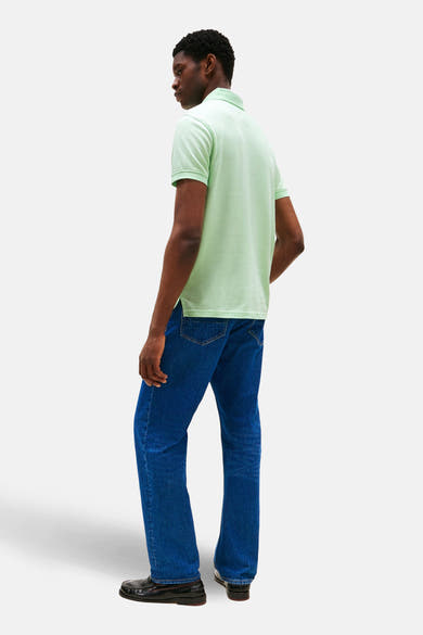 Polo vert à manches courtes de Tommy Hilfiger, porté avec un jean bleu et des mocassins noirs.