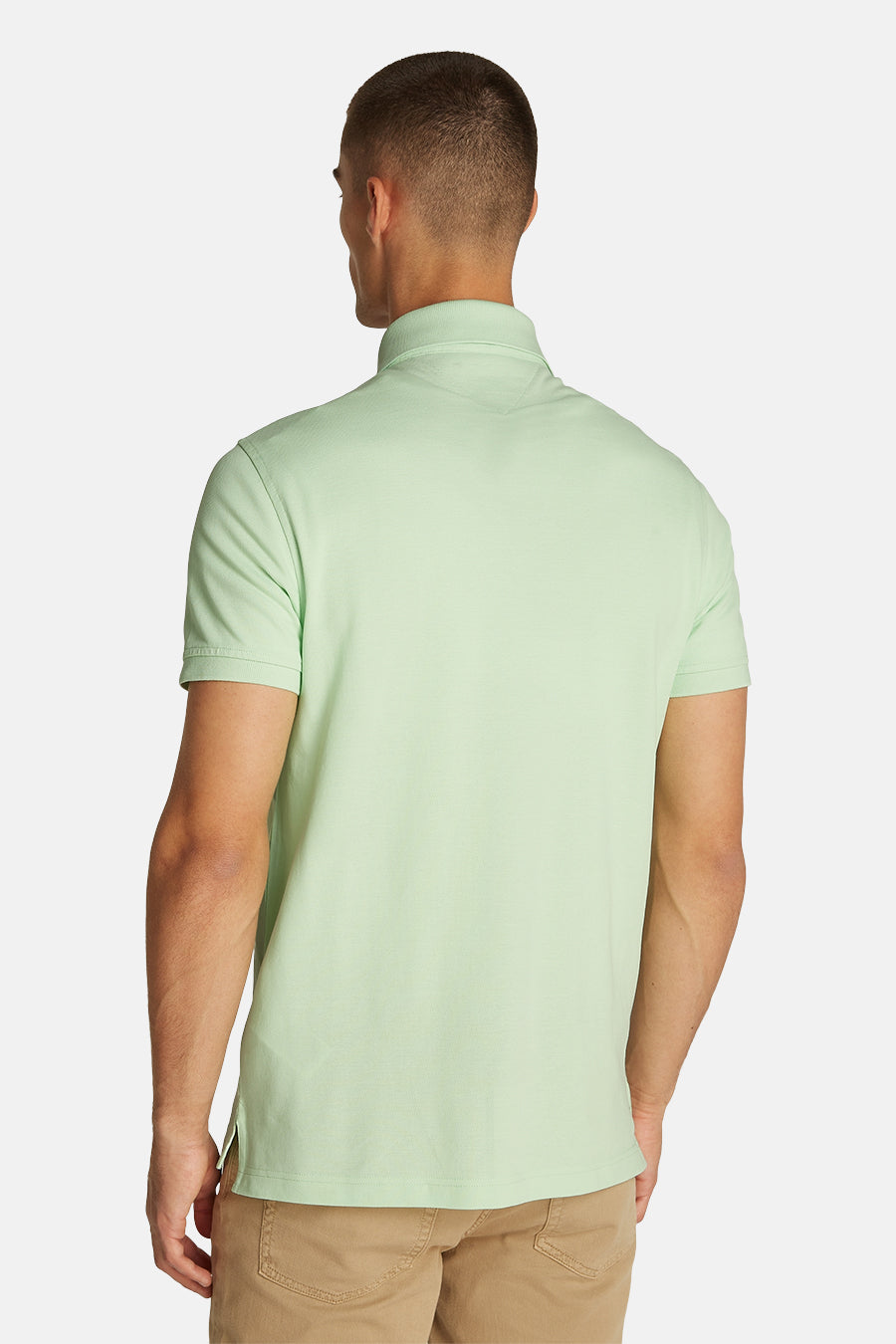 Polo vert à manches courtes de Tommy Hilfiger, vu de dos, porté avec un pantalon beige.