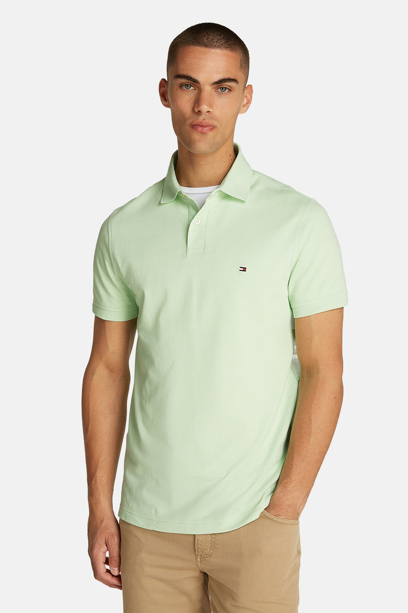 Polo vert à manches courtes de Tommy Hilfiger, porté avec un t-shirt blanc et un pantalon kaki.