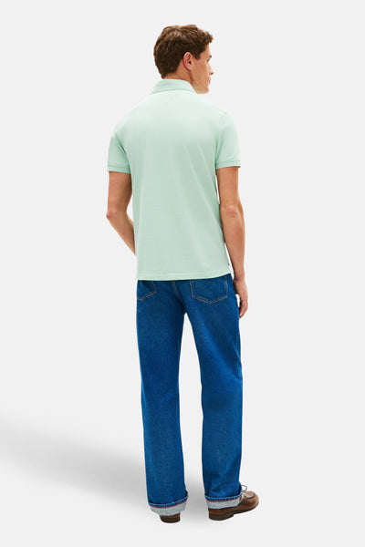 Polo à manches courtes vert de TOMMY HILFIGER, porté avec un jean bleu et des chaussures bateau marron, vue de dos.
