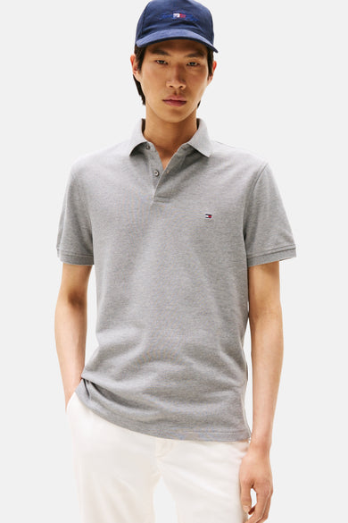 Polo gris de Tommy Hilfiger, porté avec un pantalon blanc et une casquette bleu marine.