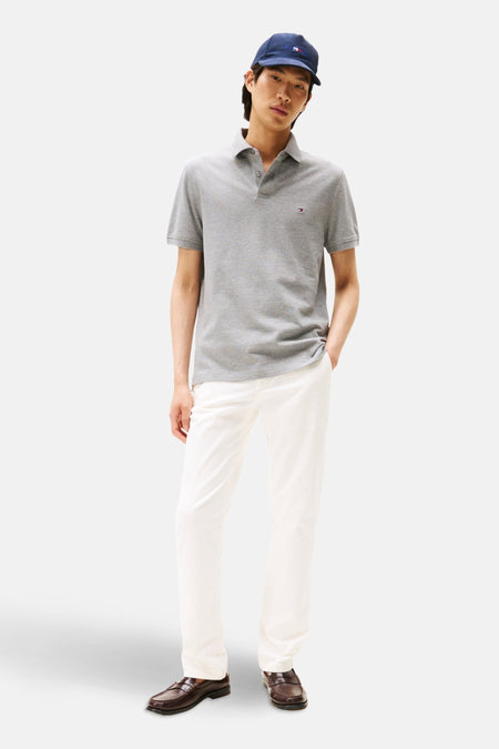 Polo gris de TOMMY HILFIGER porté avec un pantalon blanc et des mocassins.