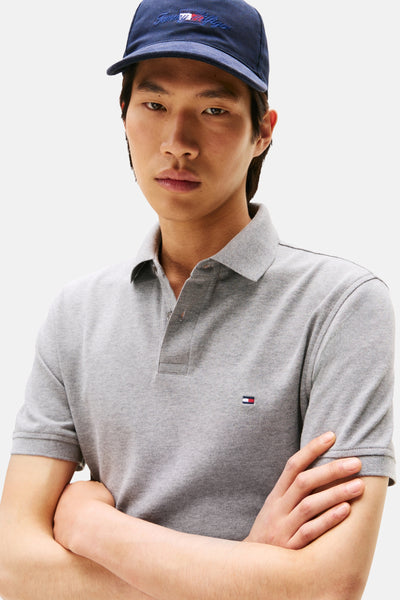 Polo gris de TOMMY HILFIGER, porté avec une casquette bleu marine.