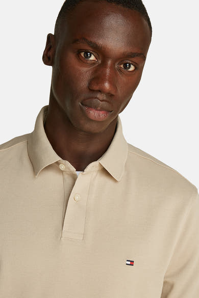 Polo beige met TOMMY HILFIGER,GERgergerger tricolorelogocolcolge door een man.