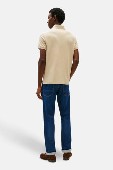 Beige korte mouw polo van TOMMY HILFIGER, gedragen met een blauwe jeans enbruroen mocassins, rugzijde.