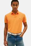Polo à manches courtes orange de TOMMY HILFIGER, porté avec un jean bleu et une ceinture tressée crème.