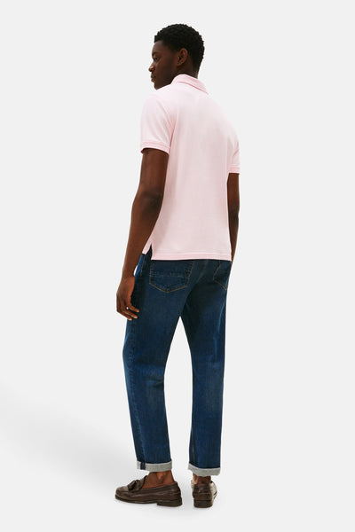 Polo rose à manches courtes de TOMMY HILFIGER, porté avec un jean bleu et des mocassins marron, vue de dos.