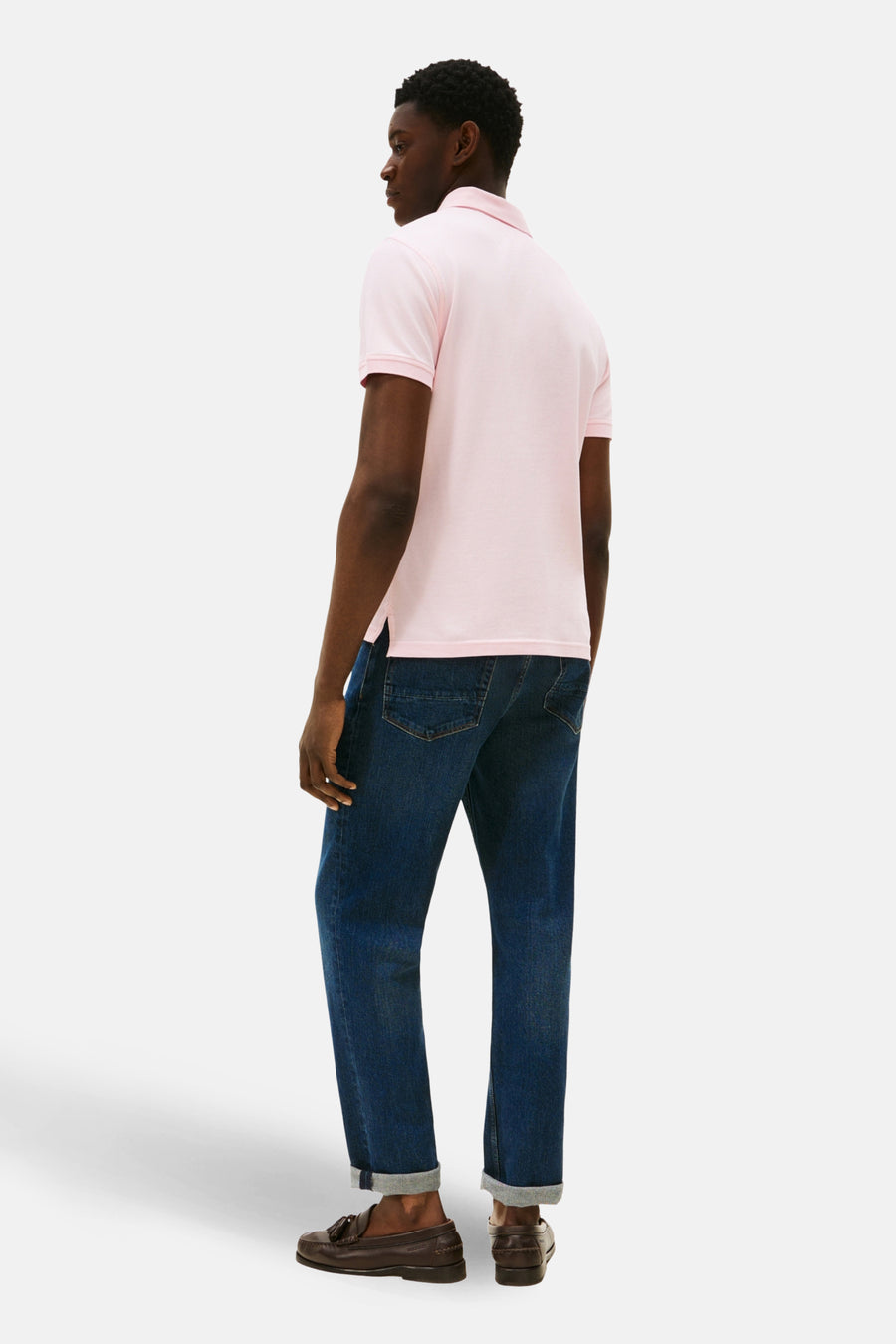 Polo rose à manches courtes de TOMMY HILFIGER, porté avec un jean bleu retroussé et des mocassins marron, vue de dos.