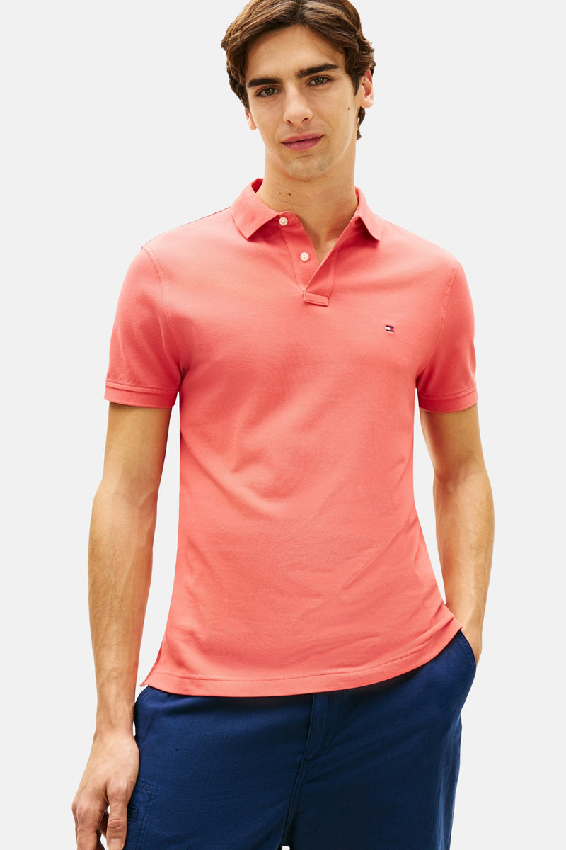 Polo rouge à manches courtes de TOMMY HILFIGER, porté avec un pantalon bleu marine uni.