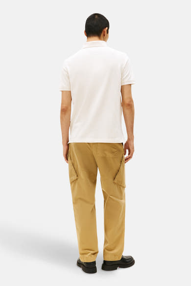 Polo-shirt in korte mouwen van TOMMY HILFIGER, gedragen met een beige cargo-pantalon en zwarte schoenen.