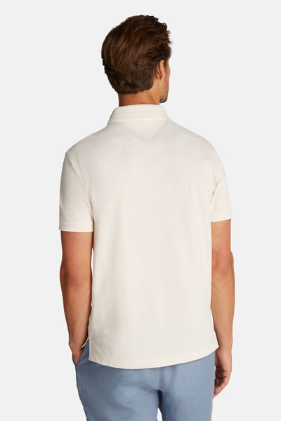 Polo à manches courtes écru de TOMMY HILFIGER, en coton texturé, porté avec un pantalon bleu clair, vue de dos.