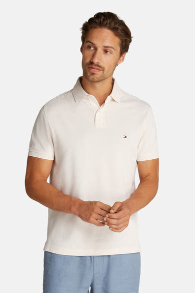 Polo wit van Tommy Hilfiger, met korte mouwen, gedragen met een beige cargo broek en zwarte mocassins.